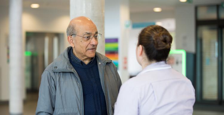 Older Asian man talking to a nurse