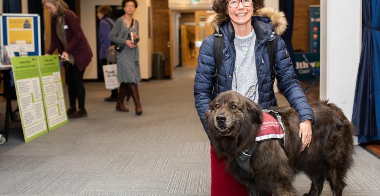 Lady in blue jacket with a brown hearing dog