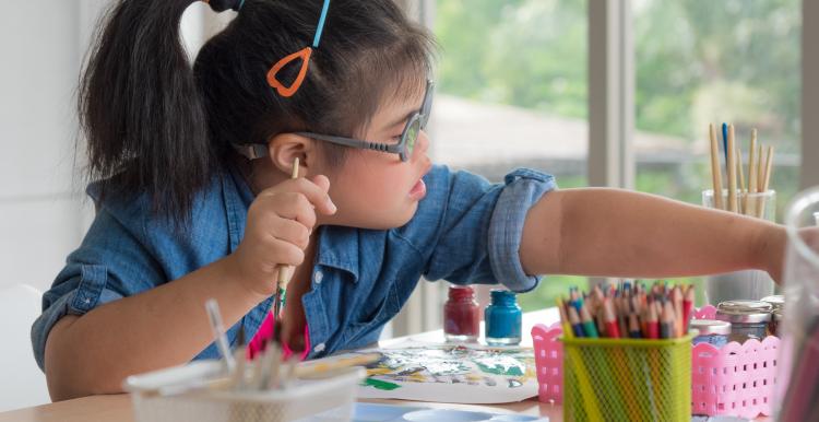 Girl reaching out for a paint brush.