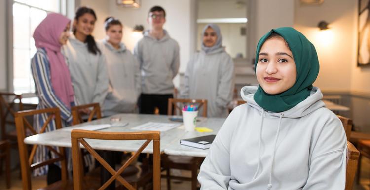 Young female wearing a headscarf sits at a table