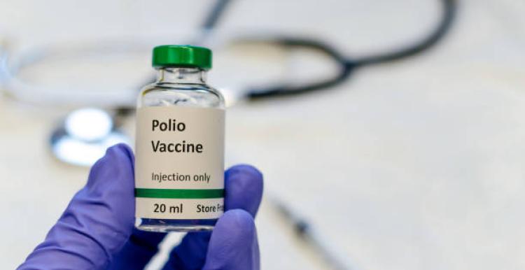 Polio vaccine bottle, stethoscope and syringe on table
