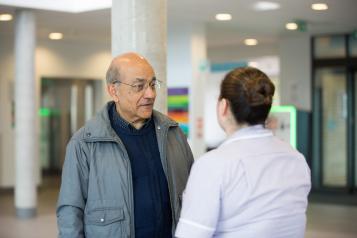 Older Asian man talking to a nurse