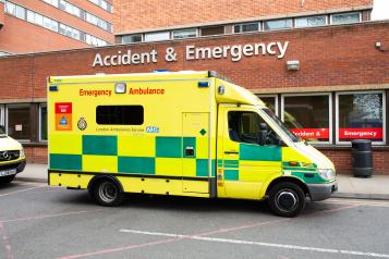 Ambulance parked front of A&E entrance of hospital.
