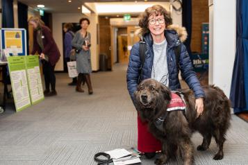 Lady in blue jacket with a brown hearing dog
