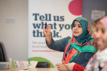 Woman wearing a green headscarf is speaking and pointing