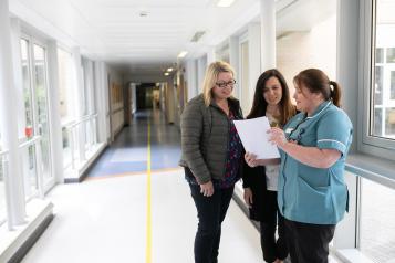 women talking to nurse in hospital hallway