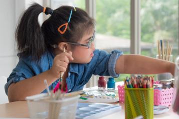 Girl reaching out for a paint brush.