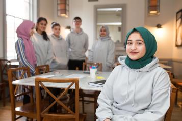 Young female wearing a headscarf sits at a table