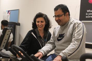 Man running on treadmill with a friendly 150Club rep coaching him.