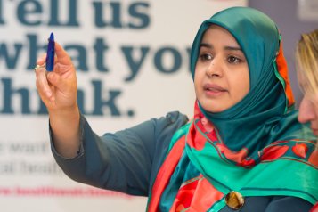 Woman wearing a hijab, speaking at an event.