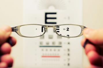 Glasses being held up infront of an eye test