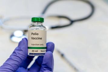 Polio vaccine bottle, stethoscope and syringe on table