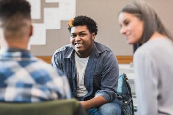 Young man smiling, talking to friendly people