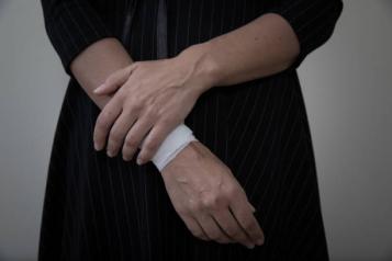 Person holding the right wrist, right wrist is wrapped with bandage covering scars