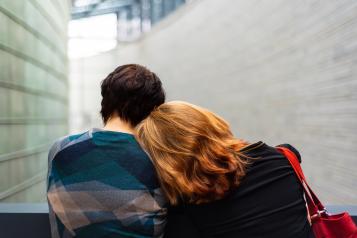 two people sitting close together leaning on each other