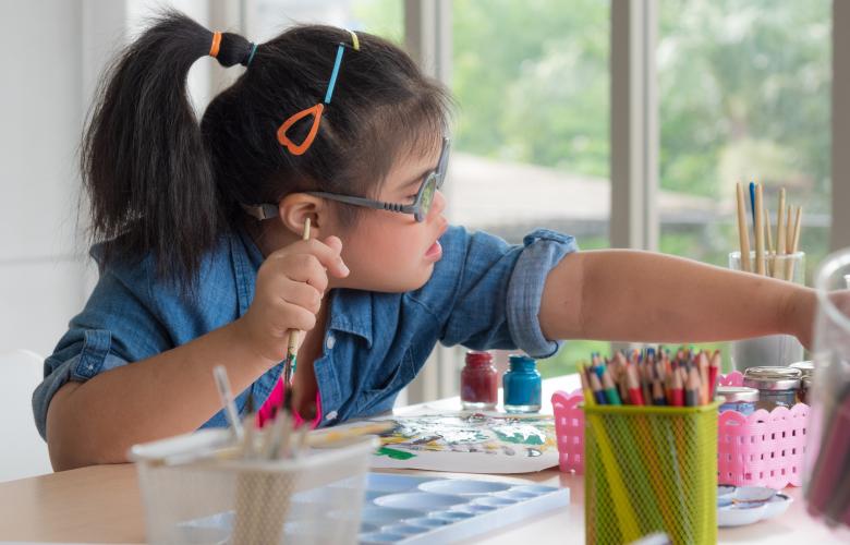 Girl reaching out for a paint brush.