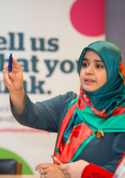 Woman wearing a hijab, speaking at an event.